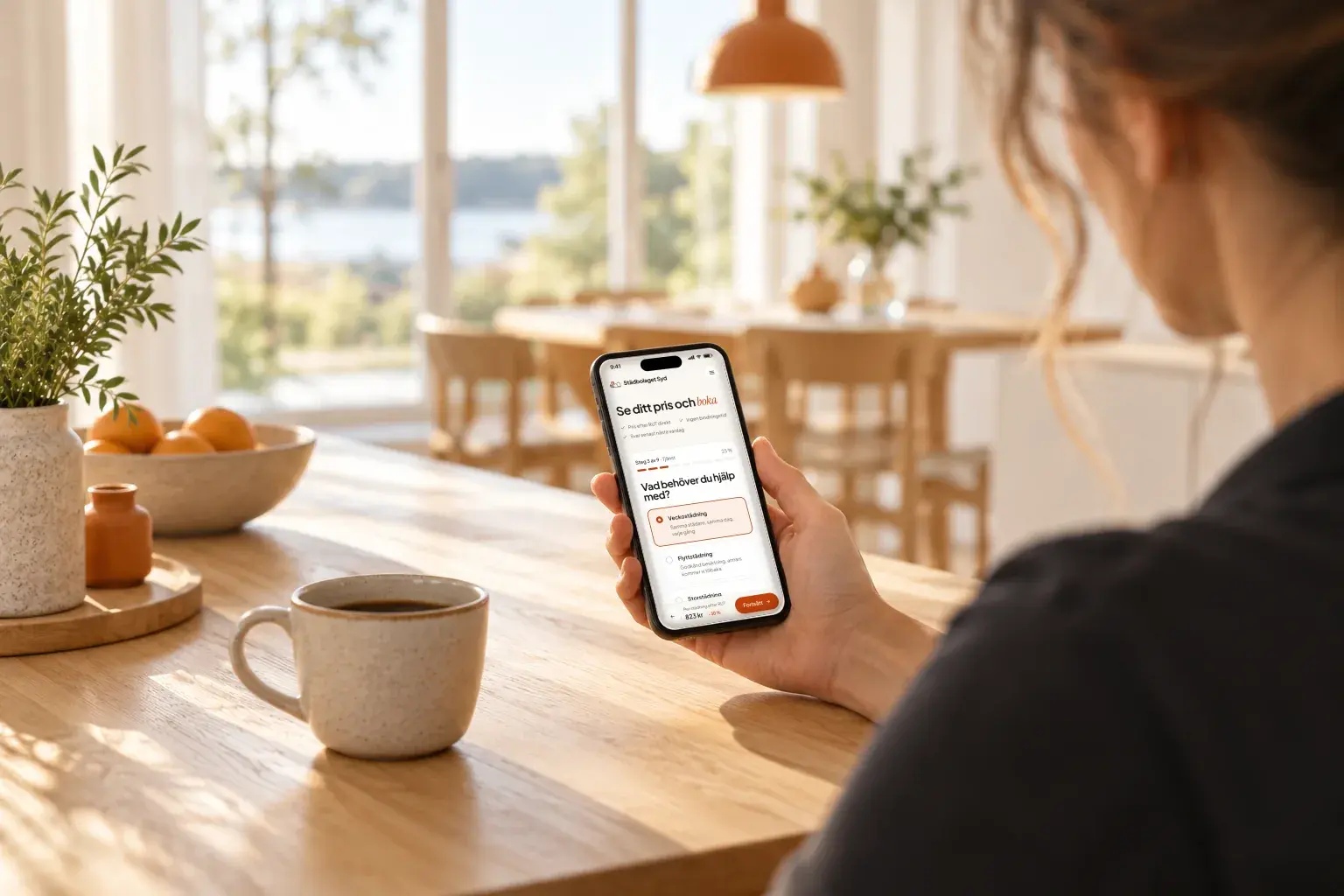 Mobil vid köksbordet som visar bokningen på stadbolagetsyd.se med pris efter RUT
